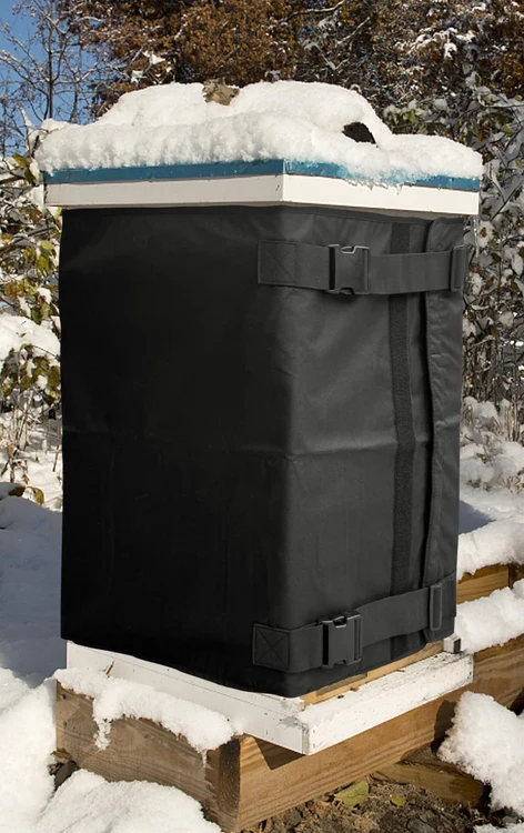 Owner-supplied photograph of a snow-covered hive with black wrap and both buckle straps visible.
