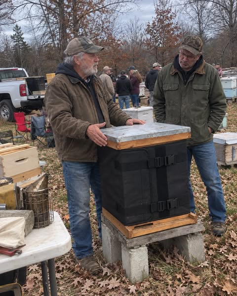 Two people beside a hive fitted with an installed black wrap.
